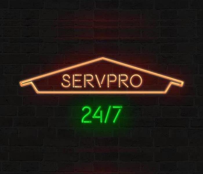 neon SERVPRO sign on black brick wall 