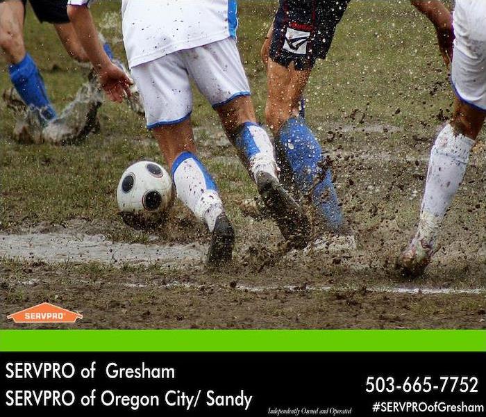 Soccer players playing in the mud. 